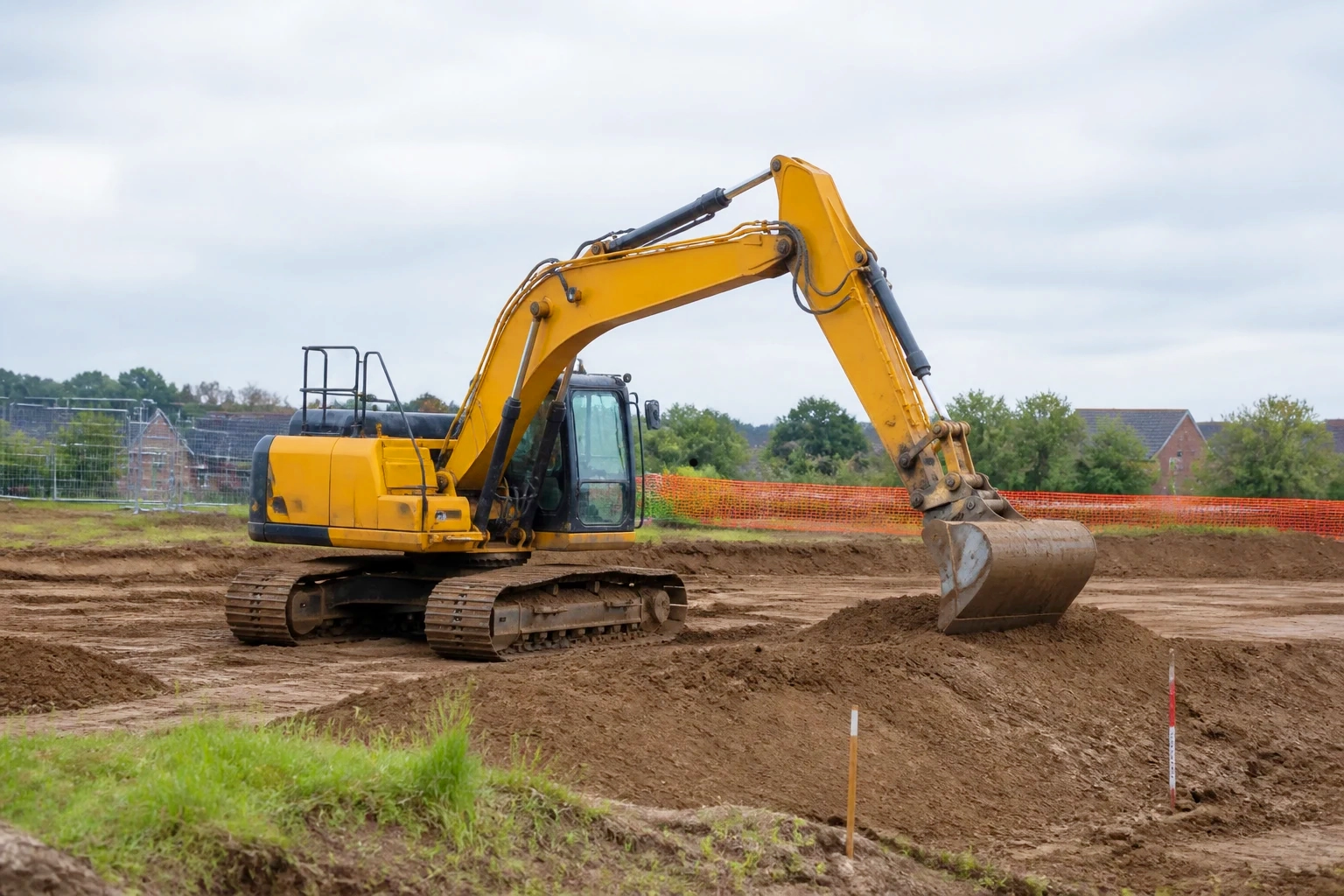 Tracked excavator carrying out earthworks and final ground profiling on a UK construction site